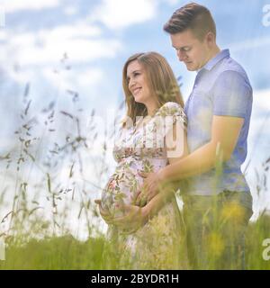 Young happy pregnant couple hugging in nature. Banque D'Images