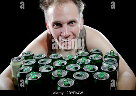 L'homme ivre et a beaucoup de boîtes de bière vides Banque D'Images