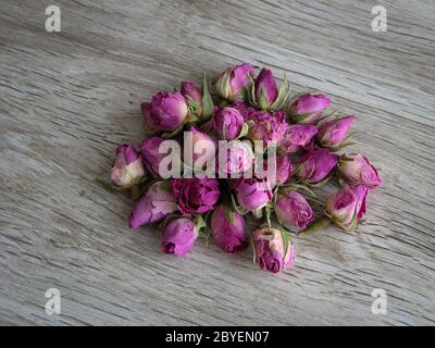 Boutons roses séchés isolés sur fond en bois. Concept d'aromathérapie. Boutons de roses séchés pour cosmétiques, aliments, médicaments et parfums. Gros plan de Rose Banque D'Images