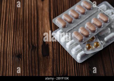 Médicament capsule forme posologique antibiotique et analgésique dans emballage blister sur fond de bois pour le concept médical, pharmaceutique et de soins de santé. Banque D'Images