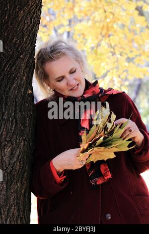 Portrait d'une femme âgée avec feuilles d'érable en automne park Banque D'Images