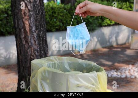 Jetez le masque chirurgical dans la poubelle publique de la rue. Le masque hygiénique se met dans les poubelles. Banque D'Images