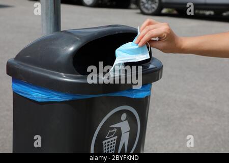 Respecter l'environnement. Jetez le masque chirurgical dans la poubelle publique de la rue. Le masque hygiénique se met dans les poubelles. Banque D'Images