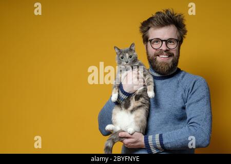 Shaggy, un homme heureux avec des lunettes, encrosse son adorable chat. Copier l'espace. Concept d'amour pour les animaux de compagnie. Banque D'Images