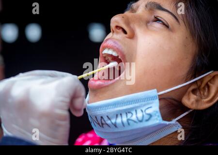 Main du médecin prenant un test de salive de la bouche de la jeune femme avec un cotton Swab. Prélèvement d'échantillons de gorge du coronavirus. Vues en gros plan. Banque D'Images