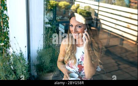 Femme parlant au téléphone portable avec une tasse de café Banque D'Images