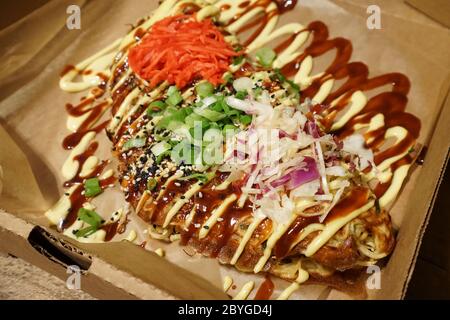 Gros plan Okonomiyaki, crêpes japonaises faites de farine, œufs, chou râpé, viande et garnies d'une variété de condiments Banque D'Images