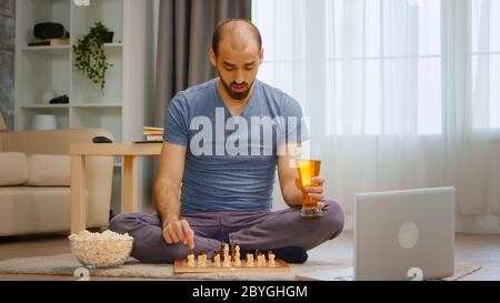 Homme jouant aux échecs sur appel vidéo avec ses amis pendant une pandémie mondiale. Banque D'Images