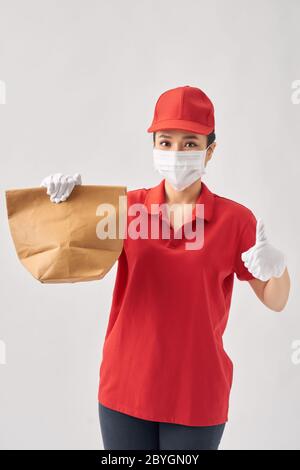 Femme qui porte un masque de protection contre les coronavirus et qui tient le sac en papier sur du blanc Banque D'Images