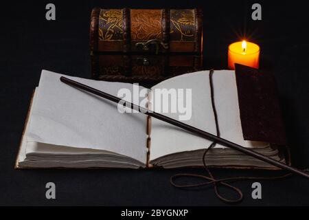 Image d'un livre magique ouvert et d'une baguette sur la table dans la pièce sombre. Banque D'Images