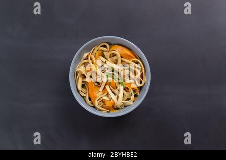 Nouilles Udon au poulet sur fond noir. Vue de dessus. Minimalisme. Cuisine japonaise. Banque D'Images