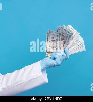 médecin dans un manteau blanc, portant des gants stériles bleus, le médecin tient un paquet d'argent papier, concept anti-corruption, pot-de-vin et le paiement pour le travail faire Banque D'Images