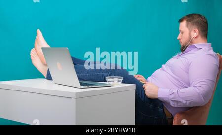 Jeune homme prenant de la musique de loisirs et d'écouter pendant qu'il est assis au bureau. Le designer masculin s'est assis tranquillement sur son lieu de travail Banque D'Images