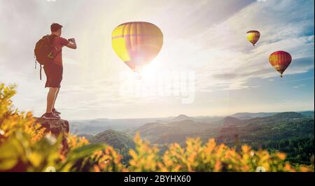 Photographe homme tient dans les mains téléphone mobile prendre des photos sur smartphone montagne avec des ballons à air chaud. Aventure touristique prise de vue sur photo Banque D'Images