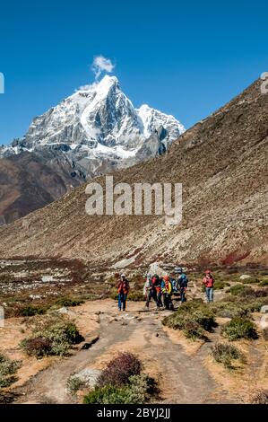 Népal. Island Peak Trek. Des randonneurs européens se dirigeant vers la colonie de Chukhung avec le pic formidable de Taboche au loin Banque D'Images