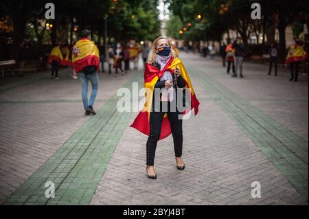 Pampelune, Espagne. 09e juin 2020. Un manifestant est vu porter un masque facial et enveloppé dans un drapeau espagnol pendant qu'elle sonne sa casséole pendant la manifestation.manifestation tenue à Pampelune, dans le nord de l'Espagne, contre la gestion effectuée par le gouvernement espagnol pendant la pandémie COVID-19. Crédit : SOPA Images Limited/Alamy Live News Banque D'Images