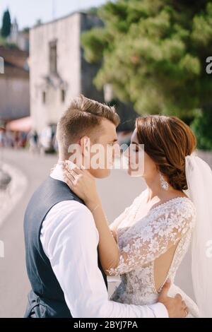 Portrait d'un couple de mariage dans la rue, la mariée épouse embrasse le marié par le cou, le marié la câle autour de la taille. Photo de mariage d'art dans Banque D'Images