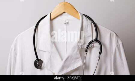 Une vieille blouse médicale et un stéthoscope sur un cintre, gros plan Banque D'Images