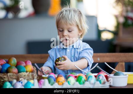 Enfants doux, frères, coloration et ponte des œufs pour Pâques dans le jardin, à l'extérieur à la maison dans l'arrière-cour Banque D'Images