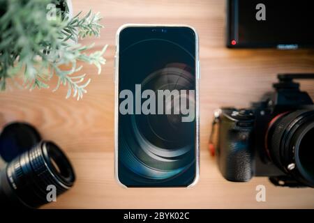 Technologie. Vue de dessus du smartphone, de l'appareil photo reflex numérique et de l'objectif sur un bureau en bois. Banque D'Images