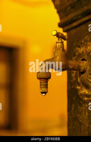 L'eau s'écoulant d'un vieux robinet dans la fontaine publique Banque D'Images