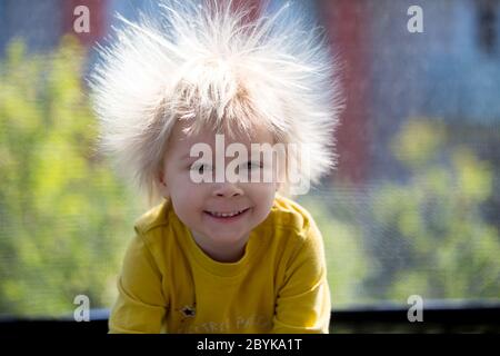 Cute little boy avec électricité statique des cheveux, avoir son portrait pris à l'extérieur sur un trampoline Banque D'Images