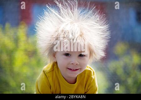 Cute little boy avec électricité statique des cheveux, avoir son portrait pris à l'extérieur sur un trampoline Banque D'Images