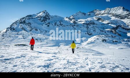 Deux randonneurs se tenant au sommet de la vallée au-dessus des montagnes. Magnifique paysage d'hiver des Alpes suisses pendant une journée ensoleillée. Hiver extérieur Banque D'Images