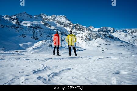 Deux randonneurs se tenant au sommet de la vallée au-dessus des montagnes. Magnifique paysage d'hiver des Alpes suisses pendant une journée ensoleillée. Hiver extérieur Banque D'Images