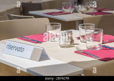 Table vide au restaurant de rue en plein air prêt pour les visiteurs avec une note indiquant que la table est réservée en italien, Italie Banque D'Images