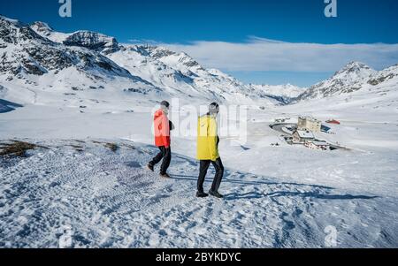 Deux randonneurs se tenant au sommet de la vallée au-dessus des montagnes. Magnifique paysage d'hiver des Alpes suisses pendant une journée ensoleillée. Hiver extérieur Banque D'Images