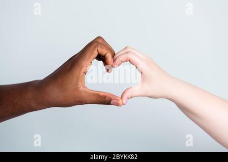 Gros plan photo de deux mains bras race différente peau couleur multinationale couple meilleurs amis anti racisme problème aider ensemble montrant l'amour de figure de coeur Banque D'Images