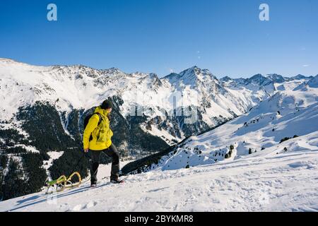 Homme avec une veste jaune montant un traîneau en bois dans une montagne enneigée. Voyage, sport d'hiver, concept de vacances. Idéal pour se divertir dans la neige ! Banque D'Images