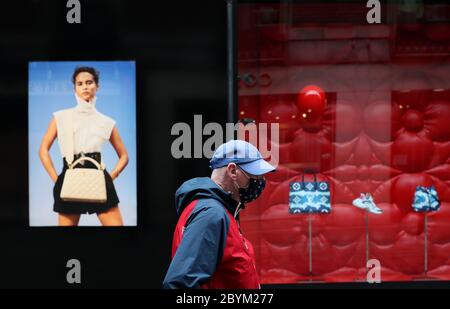 Un homme portant un masque facial de protection passe une fenêtre de magasin à Dublin, le gouvernement va intensifier sa campagne pour montrer au public comment porter correctement des masques faciaux mais ils ne seront pas rendus obligatoires, a déclaré Taoiseach Leo Varadkar. Banque D'Images