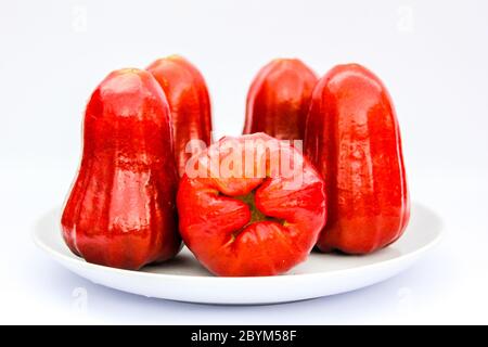 fruits rouges, pommes de rose ou chompoo isolés dans une assiette sur fond blanc Banque D'Images