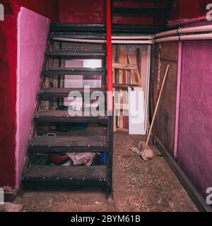 Un escalier en métal menant à un sous-sol avec des murs rouges Banque D'Images