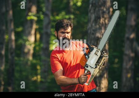 Beau jeune homme avec hache près de la forêt. Déforestation. Bûcheron dans les bois avec hache à tronçonneuse. Thème de l'agriculture et de la foresterie Banque D'Images