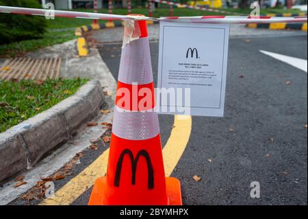 28.04.2020, Singapour, Singapour - l'entrée d'un restaurant McDonalds a été fermée avec un cône de circulation et un ruban barrière rouge et blanc Banque D'Images