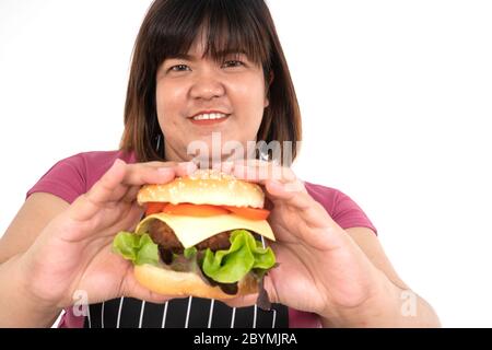 Femme en surpoids tenant un hamburger et souriant, elle est très heureuse et aime manger rapidement. Concept de troubles de l'alimentation (LIT). Banque D'Images