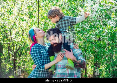 Famille marchant ensemble à travers le champ de fleurs de printemps. Une famille heureuse passe du temps ensemble dans le jardin. Famille marchant dans le champ agricole. Banque D'Images