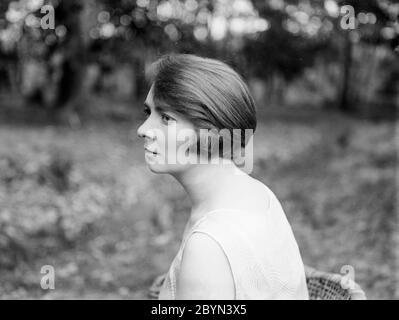 Une photographie de portrait anglais vintage des années 1920 en noir et blanc, montrant une vue latérale de la tête de jeune femme peut attirer. La photo est prise à l'extérieur avec la lumière naturelle, et montre la coiffure des années 1920. Banque D'Images