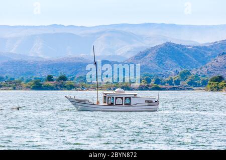 Bateau à voile sur le lac Pichola à Udaipur, Inde. Paysage avec des collines et des montagnes colorées. Banque D'Images