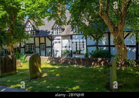 Vue sur les chalets de campagne noirs et blancs à travers les pierres tombales de chantier de l'église du village de Sainte Marie et tous les saints Grand Budworth Cheshire Banque D'Images