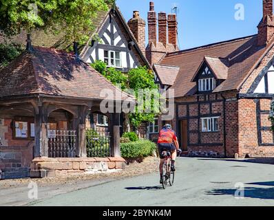 Homme à vélo dans le pittoresque et pittoresque village pittoresque de Cheshire, dans le vieux pays rural de Great Budworth, Angleterre, Royaume-Uni Banque D'Images