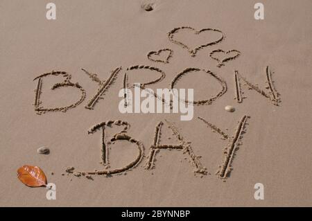Formes de coeur et inscription de Byron Bay dessinées dans le sable. Byron Bay est l'un des lieux touristiques les plus célèbres d'Australie, connu pour ses vibes fraîches, Banque D'Images