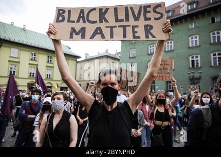 Le manifestant féminin dans un masque médical tient des pancartes avec des slogans condamnant le racisme pendant la manifestation « Black Lives Matter » à Cracovie, la plus grande ville de l'époque Banque D'Images