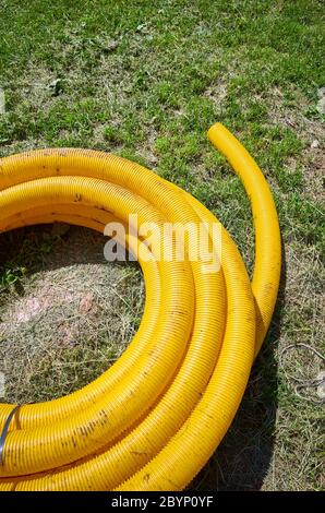 Tuyau de drainage de terre à bobine jaune sur le sol, utilisé pour enlever l'eau excessive des champs et des jardins. Banque D'Images