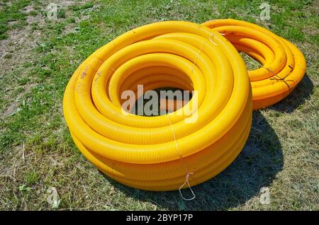 Tuyau de drainage de terre à bobine jaune sur le sol, utilisé pour enlever l'eau excessive des champs et des jardins. Banque D'Images
