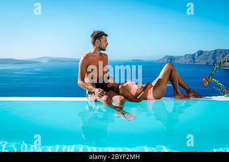 Couple en vacances de luxe en Grèce, Oia Santorini hommes et femme à la piscine à débordement de caldera donnant sur l'océan de l'île de Santorini Banque D'Images