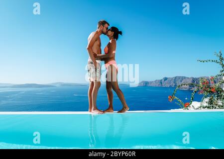 Couple en vacances de luxe en Grèce, Oia Santorini hommes et femme à la piscine à débordement de caldera donnant sur l'océan de l'île de Santorini Banque D'Images